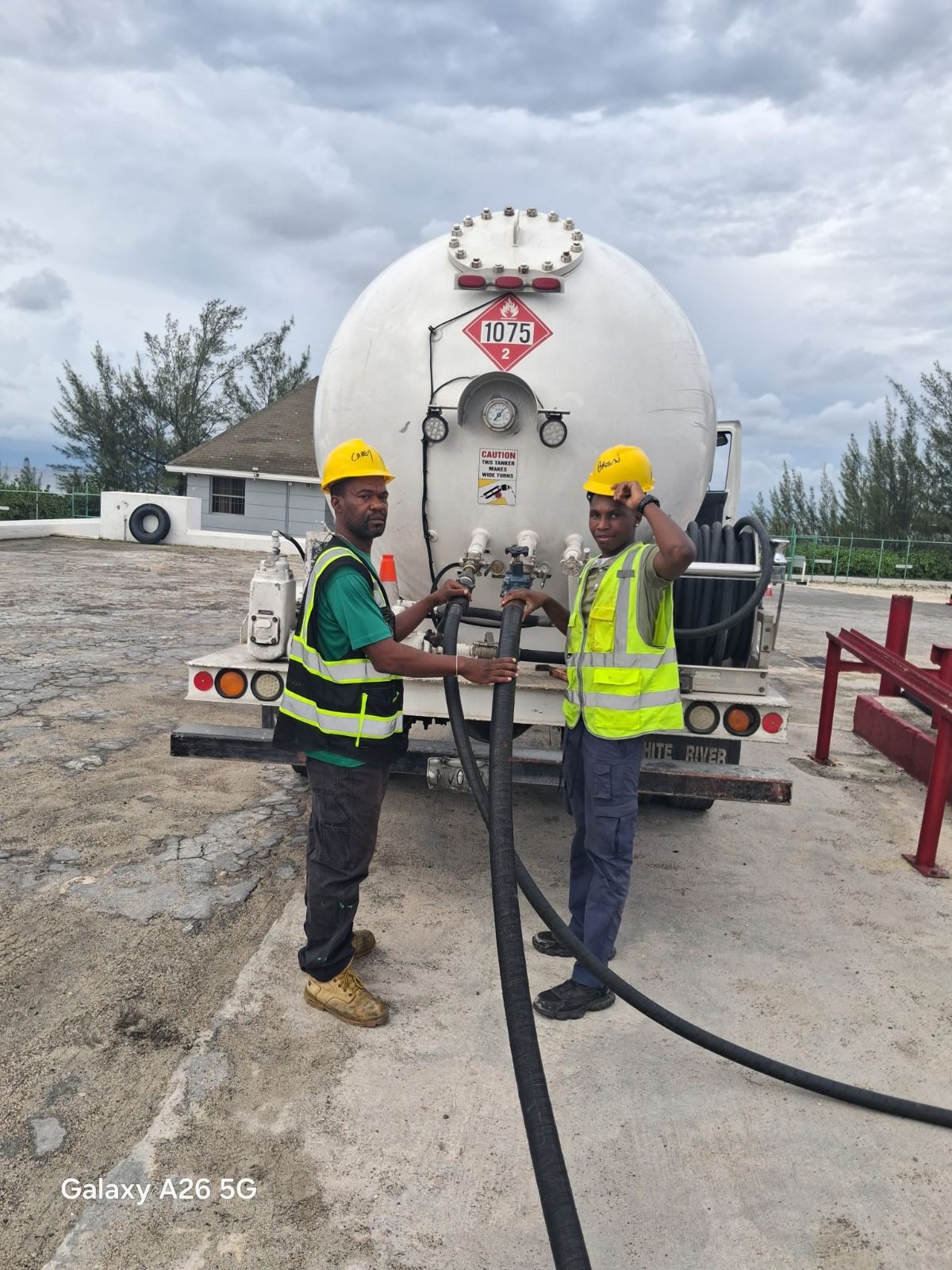 Two Caribbean Gas crew members in hi-vis vests connecting a delivery hose